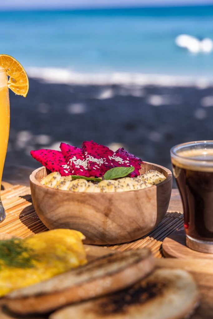 Dragon fruit and banana bowl with juice and coffee by the beach